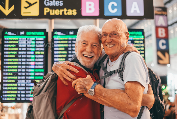 Happy couple of senior friends men hugging and goodbye in airport for arriving or departing trip