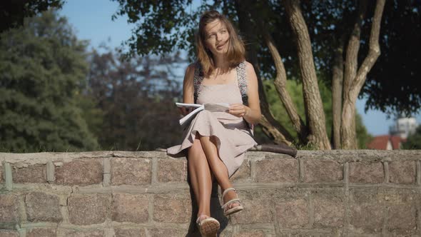 Woman reading a book near the old building alt