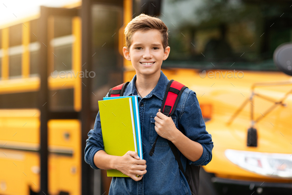 Back To School. Happy smiling preteen boy standing near school bus ...