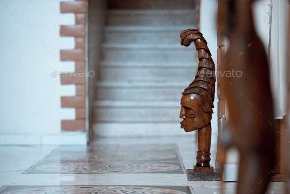 Wooden tribal sculpting near the wall with a blurred background