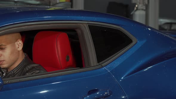 Handsome Young Man Talking on the Phone Sitting in His Car alt