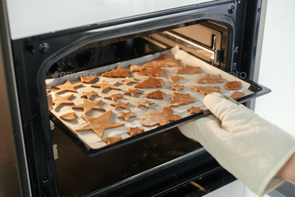 Fresh baked gingerbread cookies in christmas festive shapes on baking tray  in modern white kitchen Stock Photo by Sonyachny