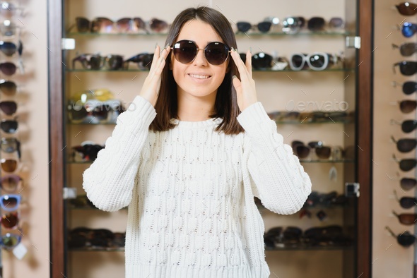 Which one is better fit me. Portrait of cheerful hesitating woman in optician store,