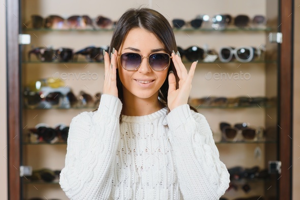Which one is better fit me. Portrait of cheerful hesitating woman in optician store