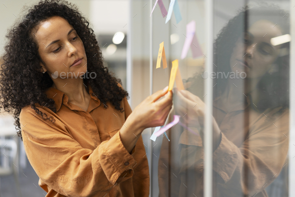 Businesswoman using sticky notes, agile methodology for productivity working in modern office