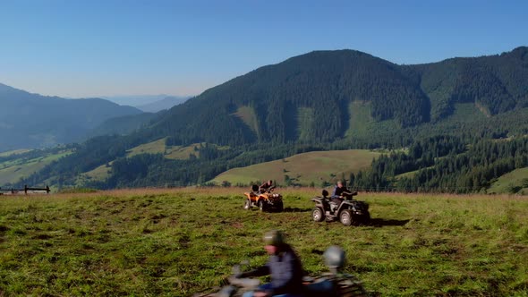 Men Driving on ATV Against Beautiful Mountains and Sky Background alt
