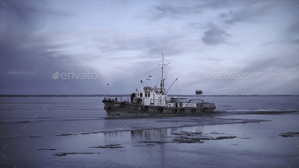 Fishing boat floats on background of cloudy winter landscape. Clip. Fishing  boat with flag sails by Stock Photo by BlackWhaleMedia