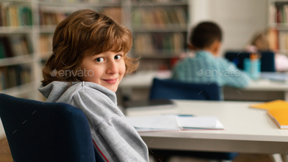 European schoolboy turning back, smiling at camera in class