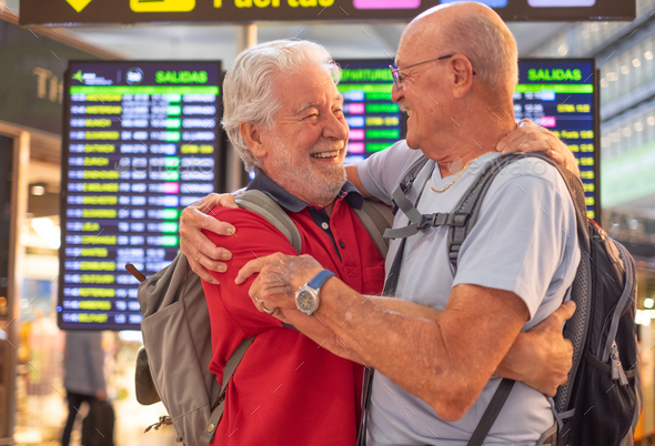 Happy couple of senior friends men hugging and goodbye in airport for arriving or departing trip