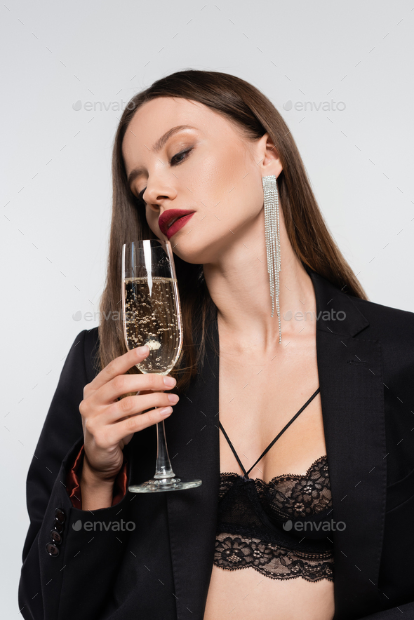 sexy woman in lace bra and black blazer holding champagne glass isolated on  grey Stock Photo by LightFieldStudios