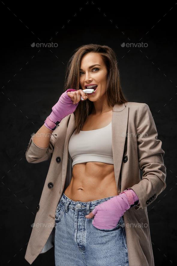 Chic sportswoman in blazer and sports bra, with boxing hand wraps and mouthguard