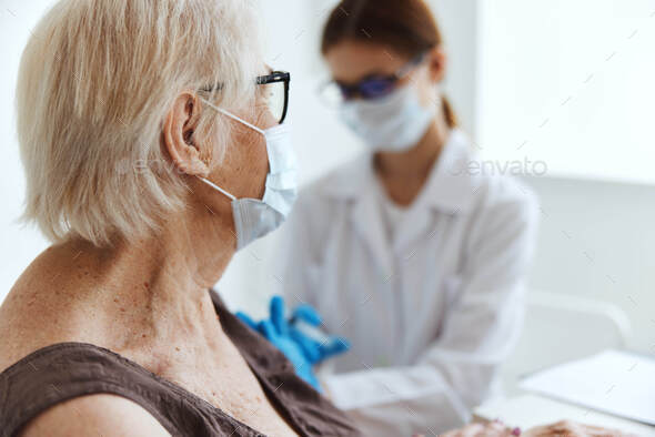elderly woman wearing a medical mask syringe injection vaccine passport hospital