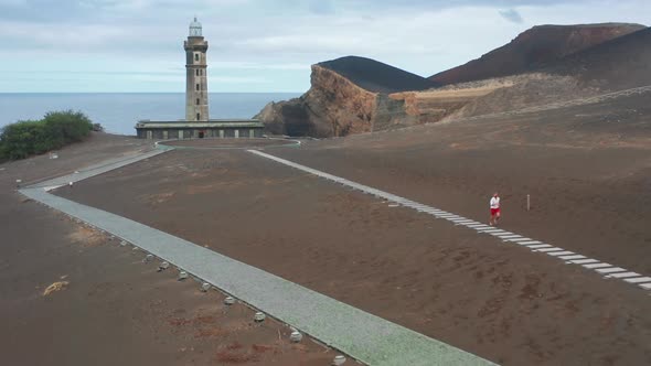 Sportsman Running on Path with with Volcano Interpretation Center of Capelinhos alt