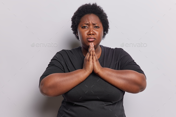 Please forgive me. Overweight dark skinned chubby woman with short curly hair keeps palms pressed