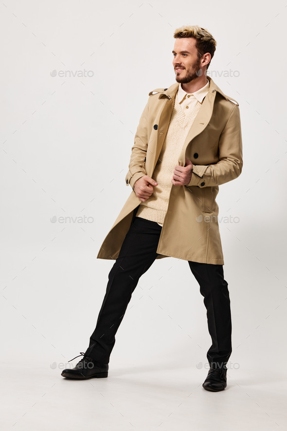 fashionable man in a beige coat trousers on a light background fashion trend of the season spring