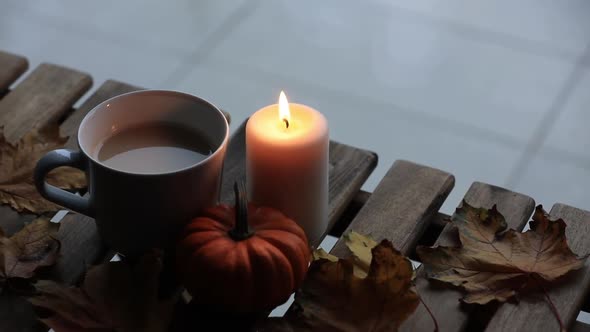 Candle, pumpkin and cup f coffee on wooden table.