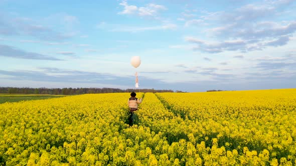 Girl Walking In Yellow Meadow With White Balloon