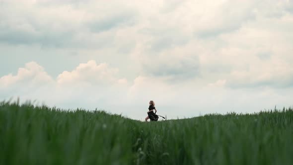 Girl In Black Dress Runs The Field. Romantic Image Of Blonde. alt