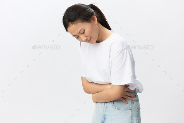 Stomach ulcer Gastritis. Tormented suffering tanned beautiful young Asian woman hugs herself hold