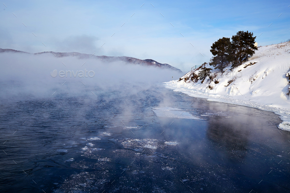 Beautiful landscape. Fog over the Angara River, snow on the bank.