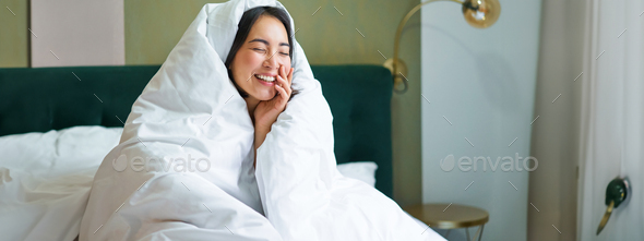 Beautiful Asian Woman Sitting On Bed Covered In Blankets And Duvet