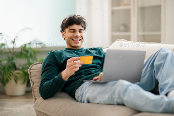 Arab Man Using Laptop And Credit Card Shopping At Home