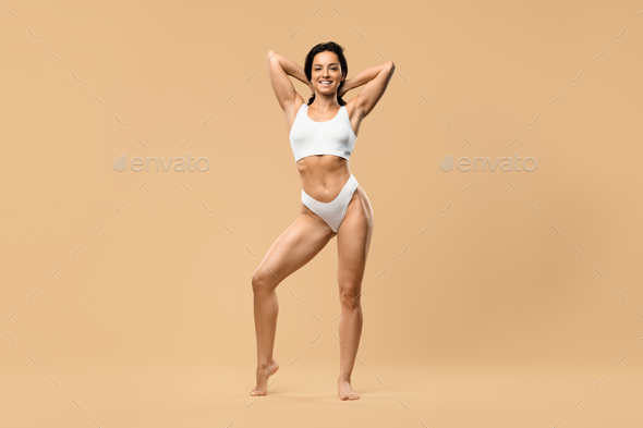 Body Sculpting. Slim Female In White Underwear Standing With Hands Behind  Head Stock Photo by Prostock-studio