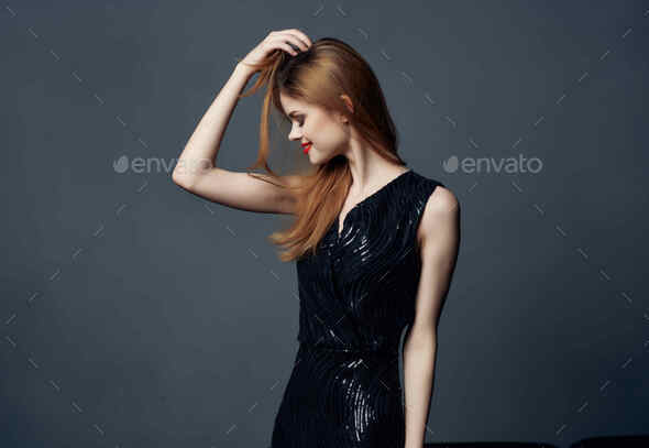 pretty woman in black dress posing on dark background luxury