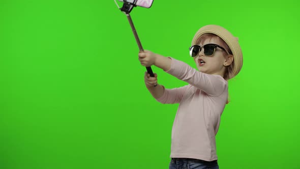 Girl Child Makes Selfie, Blogging on Mobile Phone Using Selfie Stick. Chroma Key alt