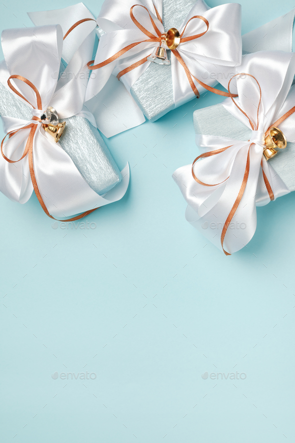 Gift boxes wrapped in blue and silver paper with white and gold ribbon bows.  Stock Photo by TaniaJoy