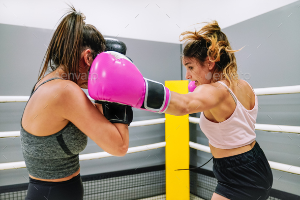 Two female boxers practicing boxing in the ring at the gym