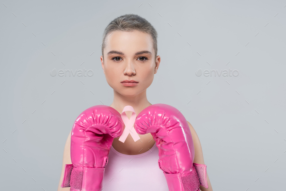 woman with short hair, in pink boxing gloves, holding breast cancer awareness ribbon isolated on