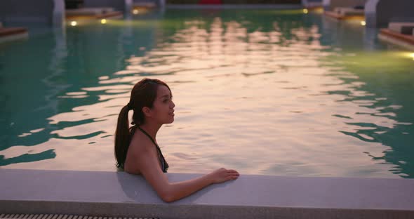 Woman enjoy in the swimming pool at sunset time