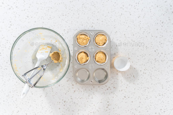 Scooping cupcake batter with a dough scoop into cupcake foil