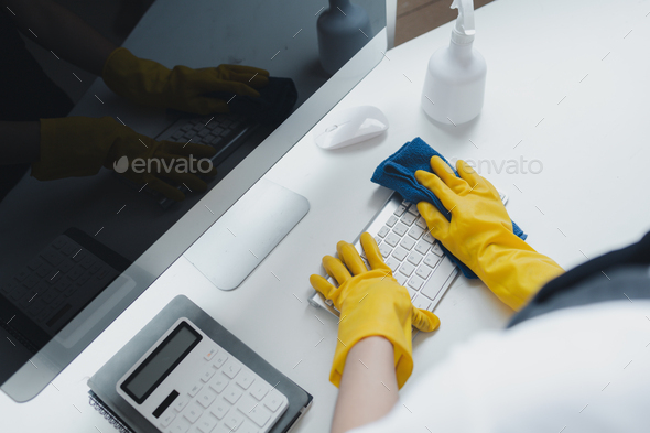 Cleaning staff wiping down office equipment, Wipe the keyboard clean with a towel and disinfectant.