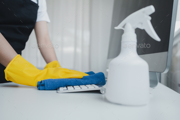 Cleaning staff wiping down office equipment, Wipe the keyboard clean with a towel and disinfectant.