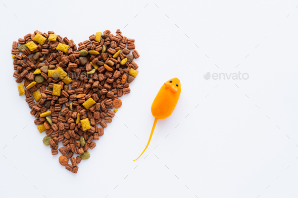 top view of dry cat food in shape of heart near near rubber toy mouse isolated on white