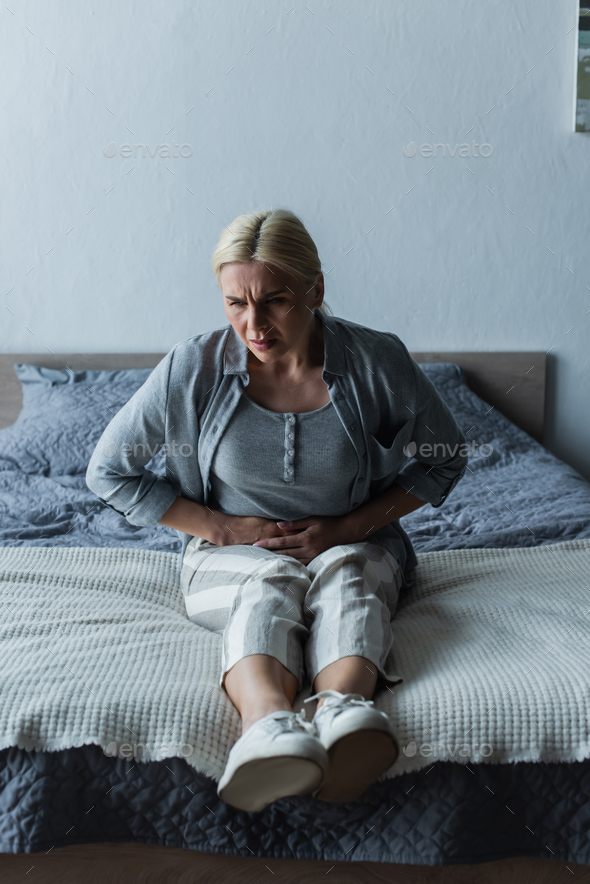 upset blonde woman with menopause suffering from abdominal pain in