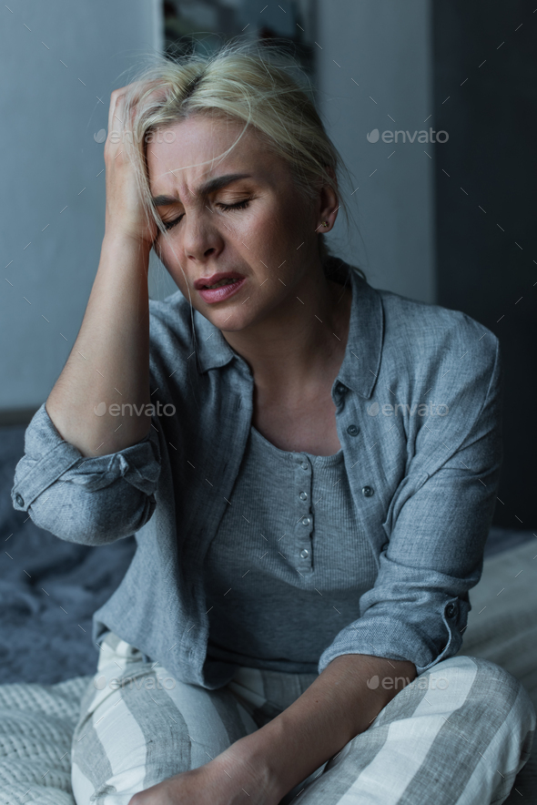 exhausted blonde woman touching head and having migraine during