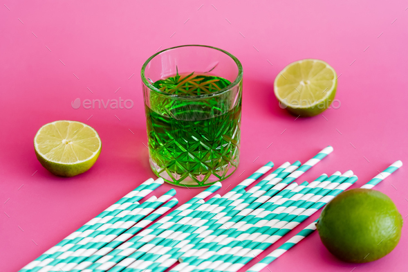green alcohol drink in glass near fresh limes on pink background Stock  Photo by LightFieldStudios