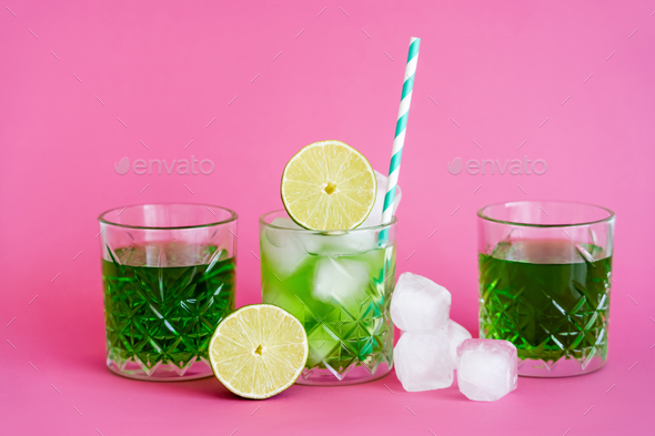 green alcohol drink in glass near fresh limes on pink background Stock  Photo by LightFieldStudios