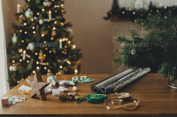 Wrapping christmas gifts. Stylish festive wrapping paper, ribbons, scissors,  bows, vintage ornaments Stock Photo by Sonyachny