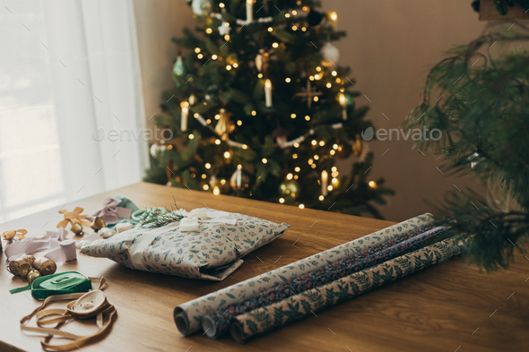 Wrapping christmas gift. Stylish festive wrapping paper, scissors, ribbons  Stock Photo by Sonyachny