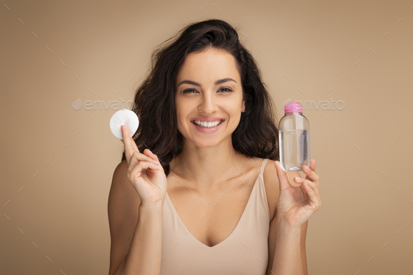 Happy pretty young brunette woman using cotton pads, micellar water