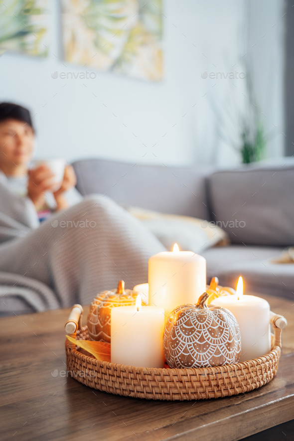 Focus on autumn fall cozy mood decor composition. Clay pumpkins, burning candles