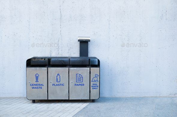 4 metal stainless steel recycle bins and trash bin with icons against grey wall. Keep environment cl