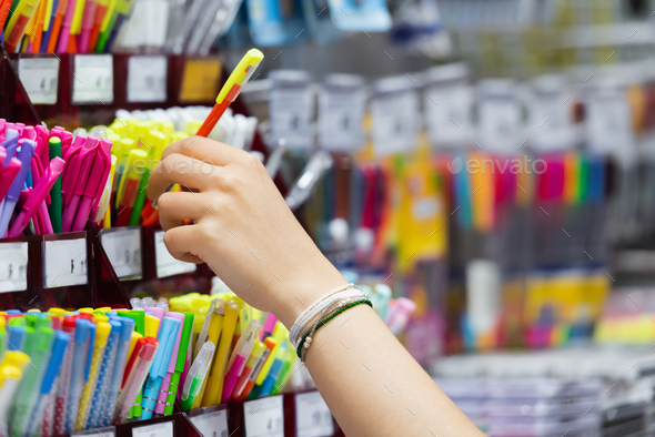 partial view of woman in beaded bracelets near colorful pencils in stationery shop