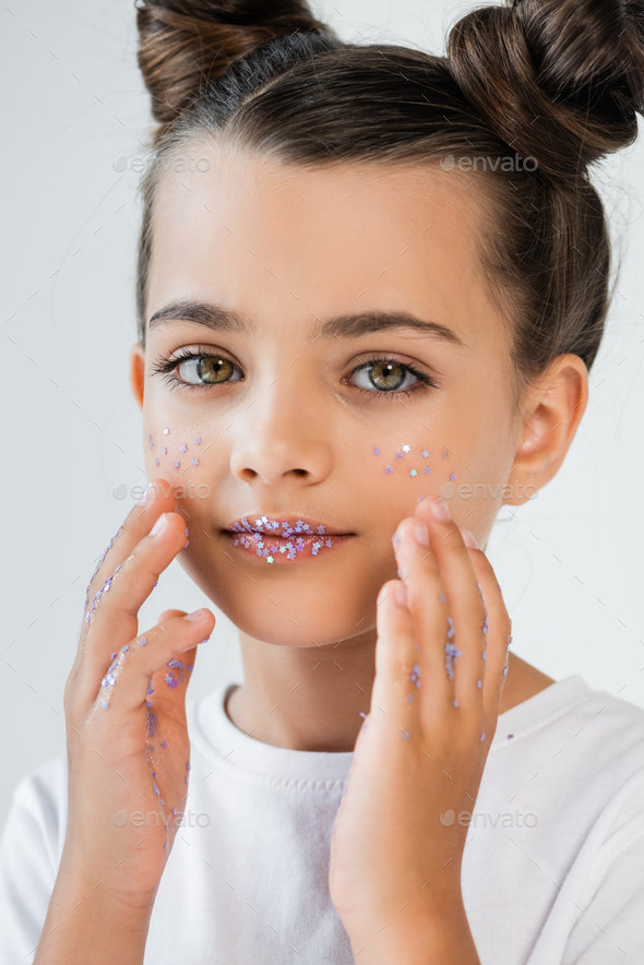 portrait of cute kid with sparkling glitter stars on face and lips looking at camera isolated on