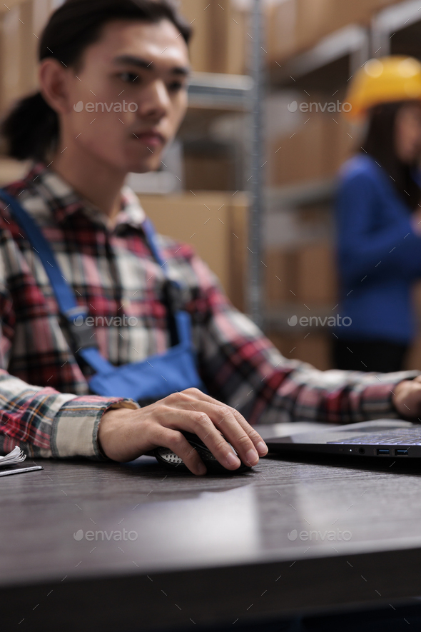 Young asian logistics manager analyzing goods supply on laptop