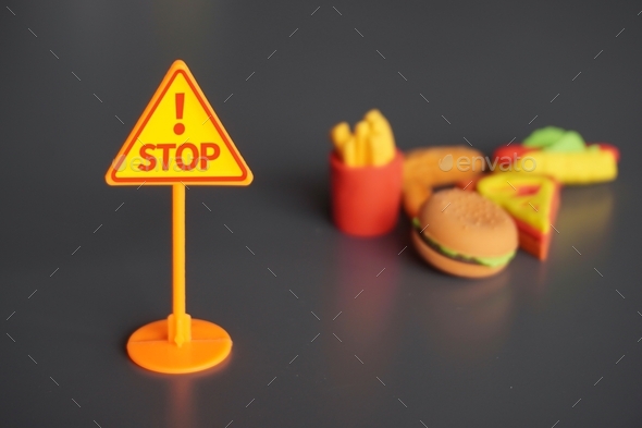 Closeup image of STOP signboard and junk foods.